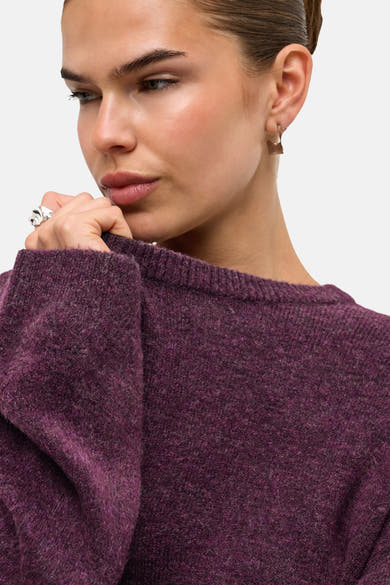 Mauve wine crewneck sweater with textured knit and ribbed neckline, close-up side view of model wearing silver ring and hoop earring