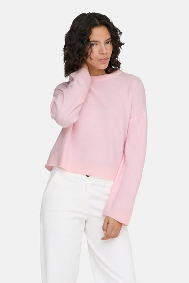 Ronde hals roze trui van ONLY, gedragen met een witte broek.