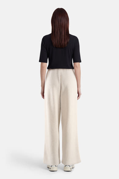 Pantalon écru de ONLY®, ample et texturé, porté avec un t-shirt noir, vue de dos.