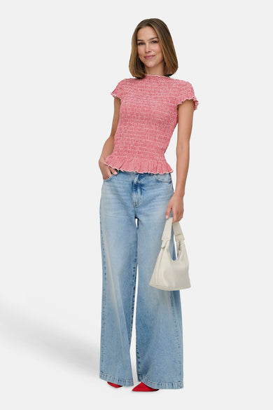 T-shirt rouge à smocks de ONLY, avec motif à carreaux et manches courtes volantées, porté avec un jean large et un sac à main blanc.