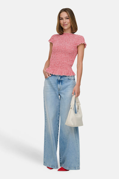 T-shirt rouge à smocks de ONLY, avec motif à carreaux et manches courtes volantées, porté avec un jean large et un sac à main blanc.