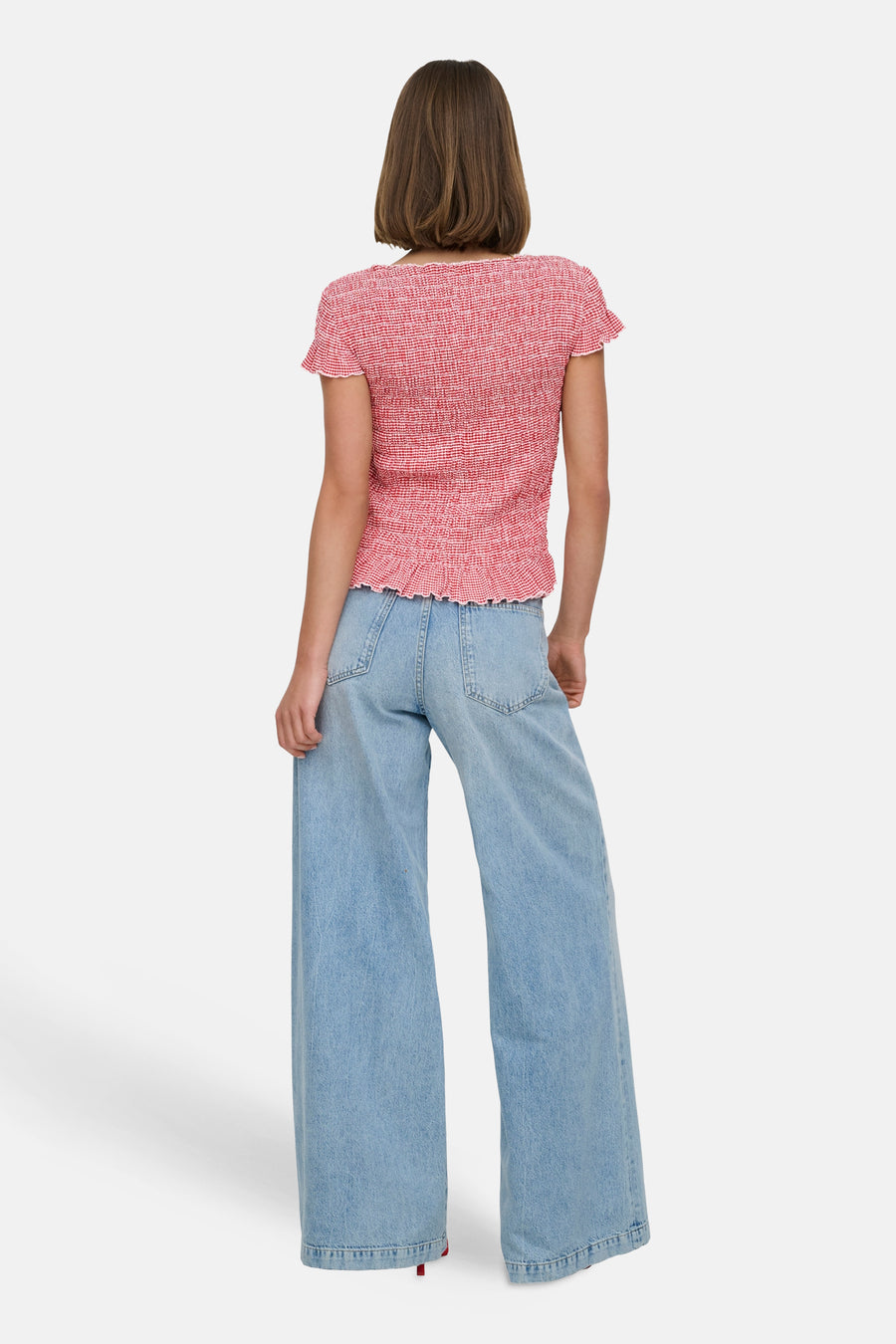 T-shirt rouge à carreaux, de ONLY®, avec des manches courtes à volants, porté avec un jean ample.