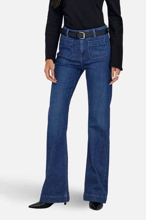 Jean évasé en denim bleu foncé de ONLY®, porté avec une ceinture noire et un haut noir à manches longues.