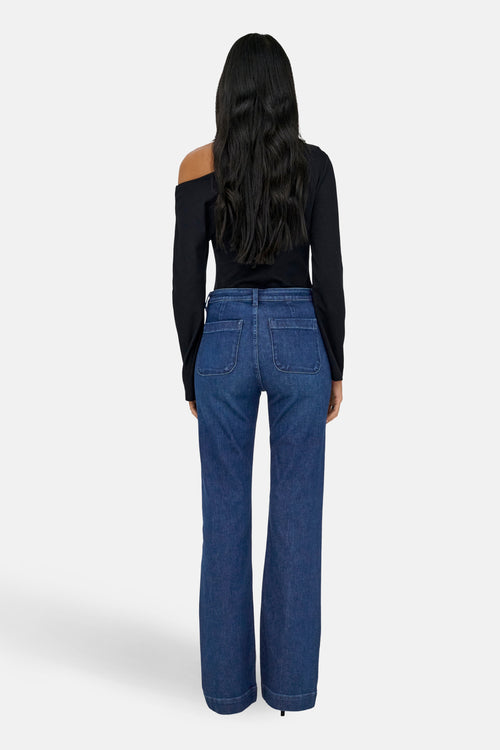 Jean évasé en denim bleu foncé de ONLY®, porté avec un haut noir à une épaule.
