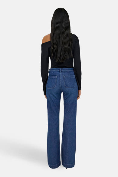 Wijd uitlopende jeans in donkerblauw denim van ONLY®, gedragen met een zwart one-shoulder topje.