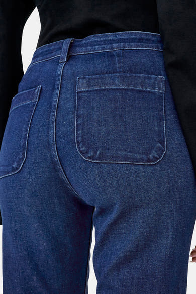 Donkerblauwe flared jeans van ONLY®, met opgestikte zakken aan de achterkant, gedragen met een zwart shirt met lange mouwen.