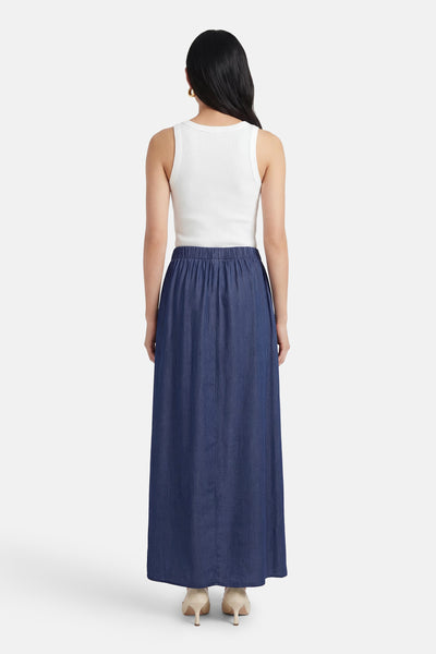 Lange spijkerrok in donkerblauw van JDY, met elastische tailleband, gedragen met een witte tanktop.
