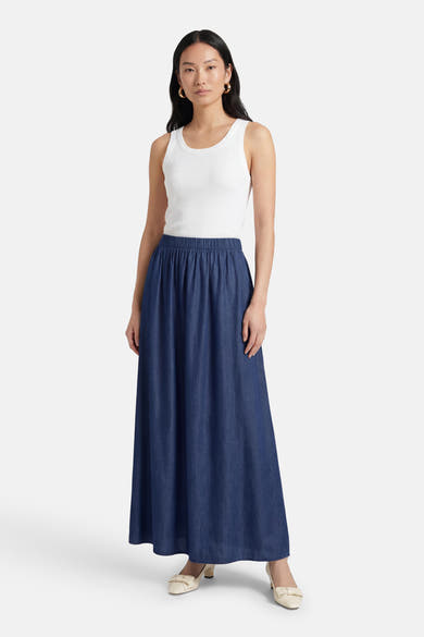 Lange donkerblauwe spijkerrok van JDY, gedragen met een witte geribbelde tanktop en crèmekleurige pumps.