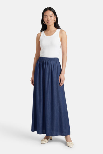 Lange donkerblauwe spijkerrok van JDY, gedragen met een witte geribbelde tanktop en crèmekleurige pumps.