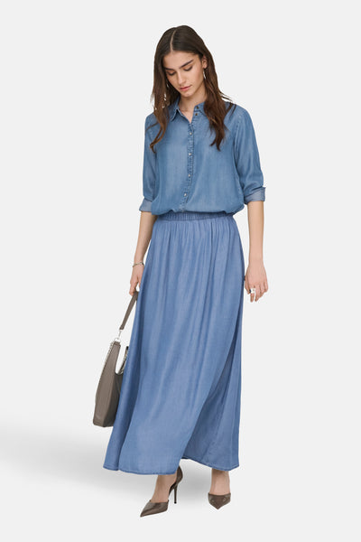 Jupe longue en denim bleu moyen de JDY, avec taille élastique et portée avec un chemisier assorti et un sac à main gris.