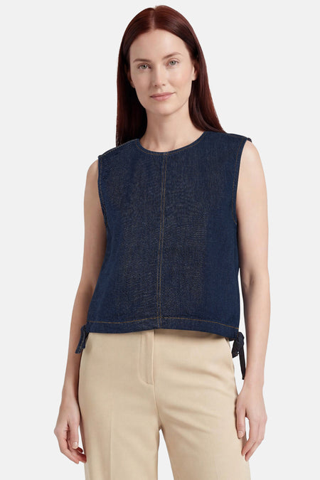 Top sans manches en jean bleu foncé de ONLY® avec col rond, surpiqûres contrastantes et liens à nouer sur les côtés, porté avec un pantalon beige.