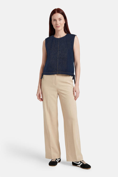 Top sans manches en jean bleu foncé de ONLY® avec détails à nouer sur les côtés et coutures contrastantes, porté avec un pantalon beige.