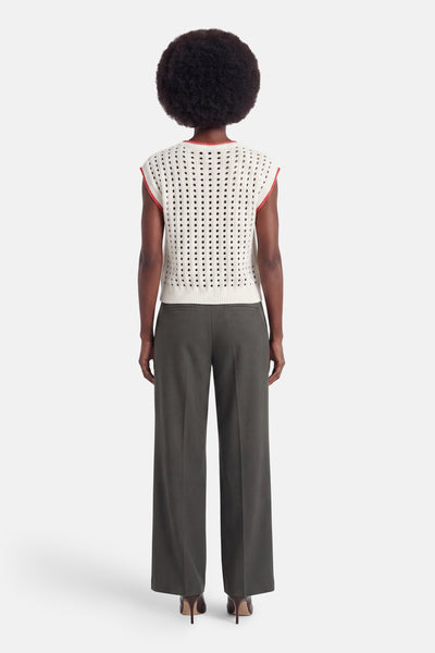 Cream perforated knit sleeveless top with red trim, back view, paired with olive wide-leg trousers and brown heels