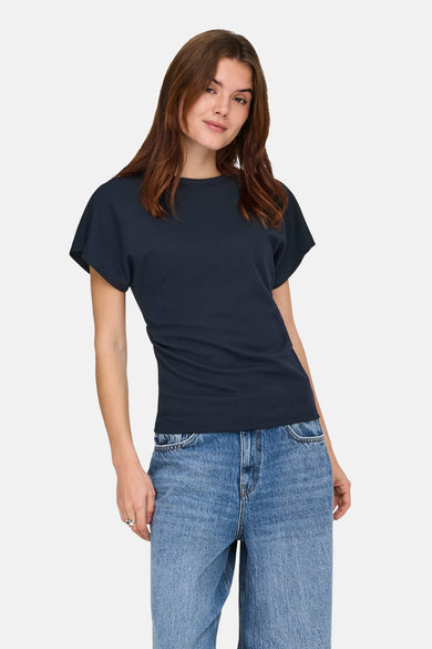 Blauw T-shirt met korte mouwen van ONLY, gedragen met een wijde jeans en witte sportschoenen.