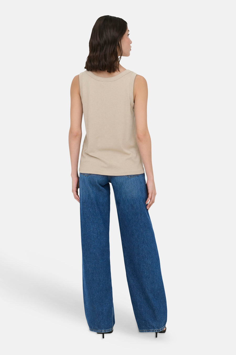 Beige mouwloos topje van JDY, achterkant met wijde jeans en hakken.