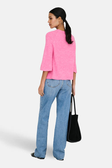 Pull à col rond rose de JDY, manches courtes, porté avec un jean ample et un sac noir.
