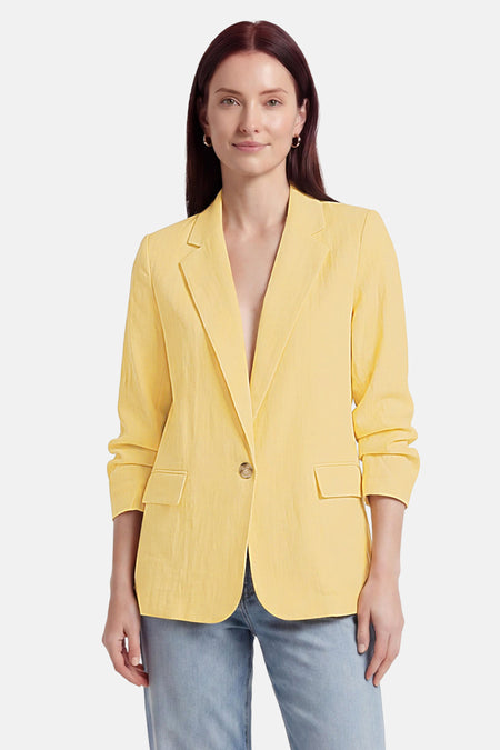 Gele blazer van ONLY® met opgerolde mouwen, één knoop, zakken en gedragen met een spijkerbroek en zwarte hakken.
