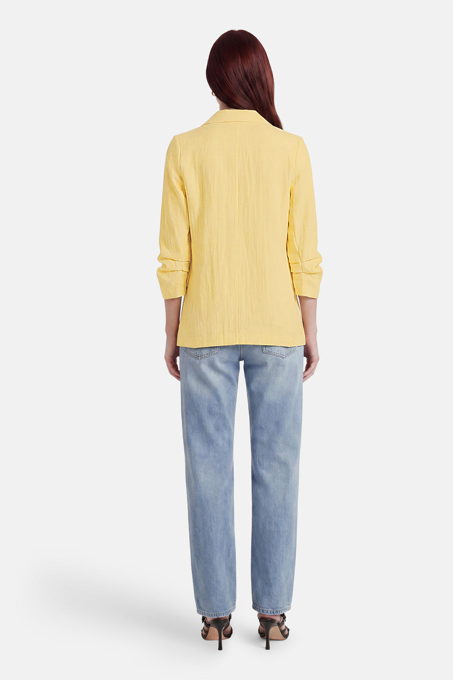 Blazer jaune de ONLY® avec manches retroussées, porté de dos sur un jean et des sandales à talons.