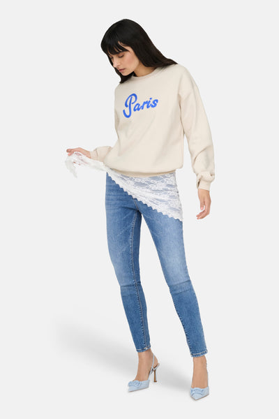 Sweat-shirt beige à col rond de ONLY®, porté avec un jean bleu et des chaussures à talons clairs.

