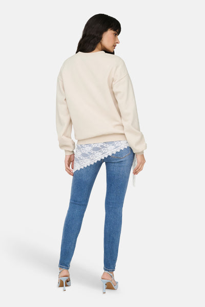 Beige trui van ONLY, versierd met witte kant, gedragen met een blauwe spijkerbroek en blauwe hoge hakken, achterzicht.