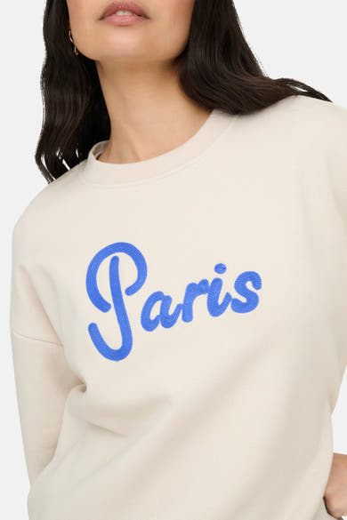 Sweat-shirt beige col rond de ONLY, avec le mot « Paris » brodé en bleu sur le devant.