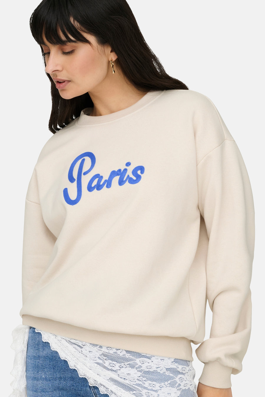 Sweat beige de ONLY, avec le mot « Paris » en bleu brodé sur le devant.