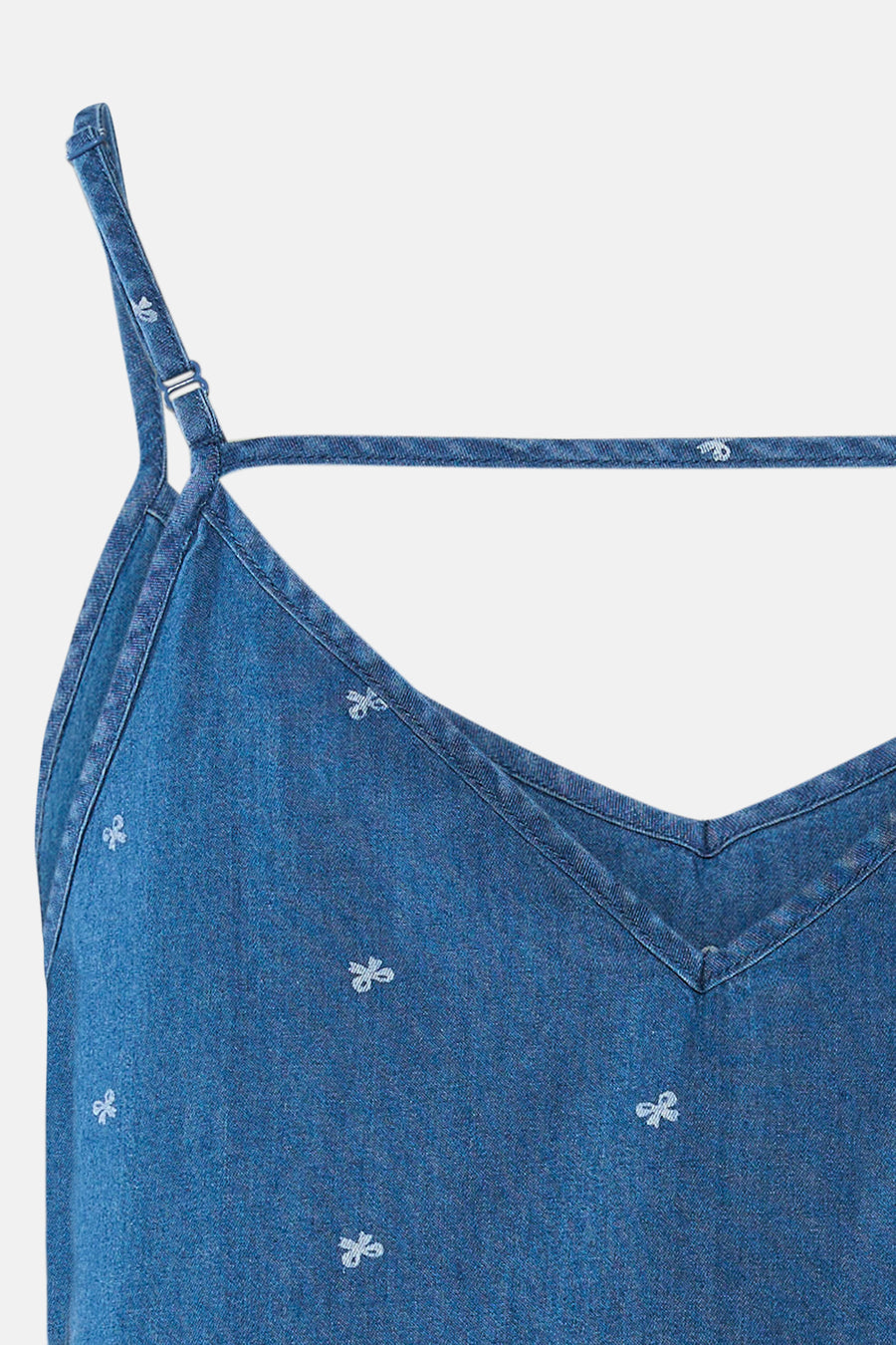 Débardeur bleu denim moyen de ONLY®, en gros plan, avec bretelles fines ajustables, un col en V, une bride arrière et un motif de nœuds blancs.