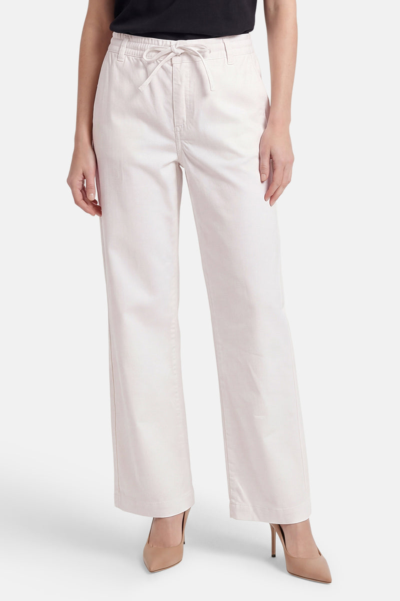 Pantalon blanc large de ONLY avec taille élastiquée et cordon, porté avec des escarpins nude.