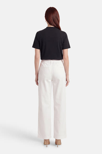 Pantalon blanc de ONLY®, vue de dos, coupe large avec poches arrière, porté avec un t-shirt noir et des talons beiges.