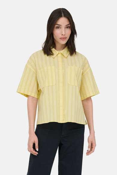 Chemise à manches courtes jaune de JDY à rayures verticales fines, avec deux poches plaquées, portée avec un pantalon noir.