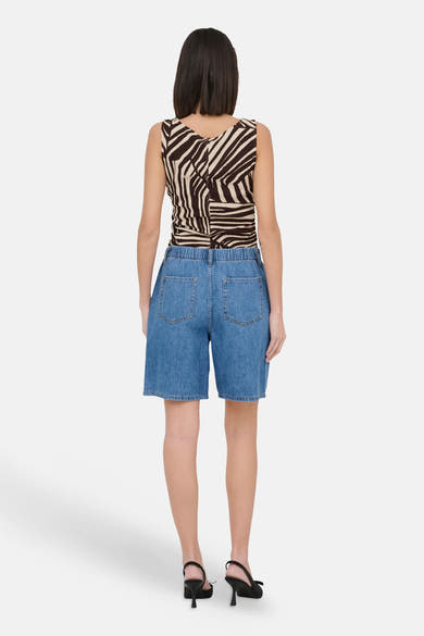 Lichtblauwe spijkerbroekshorts van JDY, achterkant, met elastische tailleband en achterzakken, gedragen met een gestreept hemdje.