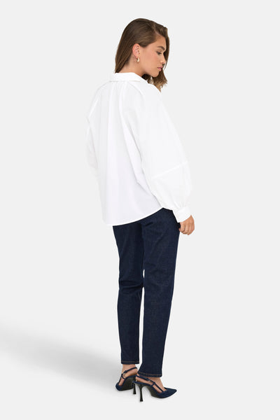 Wit overhemd met lange mouwen van ONLY, gedragen met een donkerblauwe jeans en bijpassende pumps.