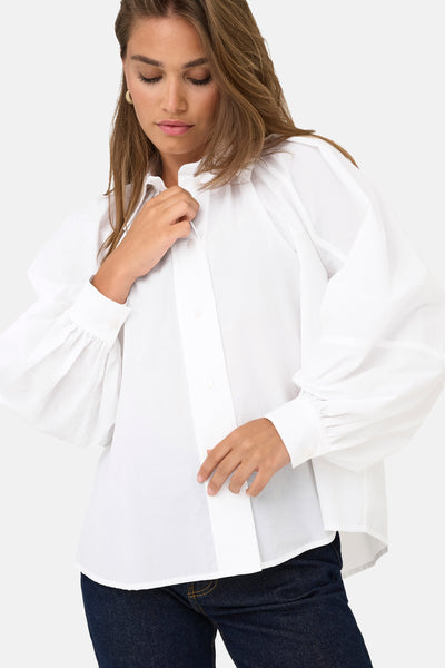 Chemise blanche à manches longues de ONLY, avec des manches bouffantes et une coupe décontractée, portée avec un jean.
