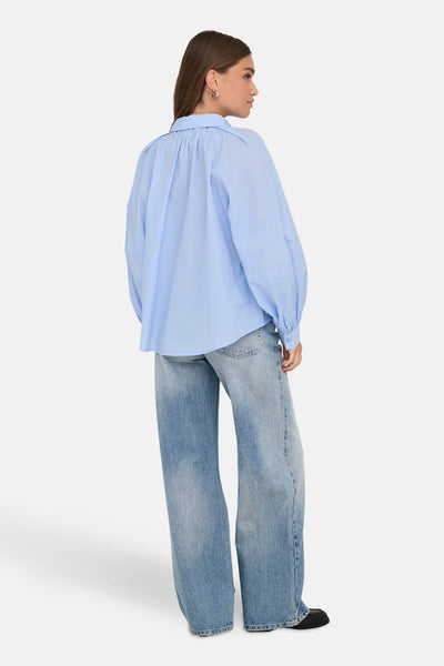 Blauwe blouse met lange mouwen van ONLY, gedragen met een wijde, uitgewassen spijkerbroek, achtergezicht.