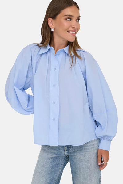 Chemisier bleu à manches longues de ONLY, porté avec un jean décontracté et des boucles d'oreilles carrées