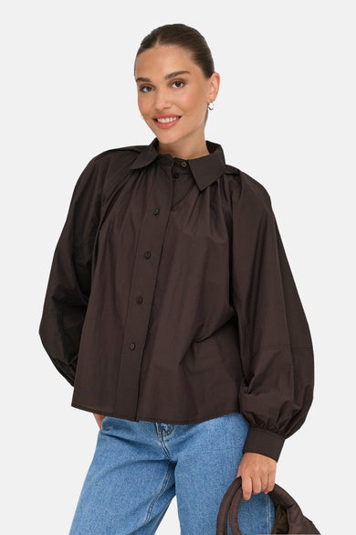 Chemise à manches longues brune de ONLY, portée avec un jean bleu clair et tenant un sac marron.