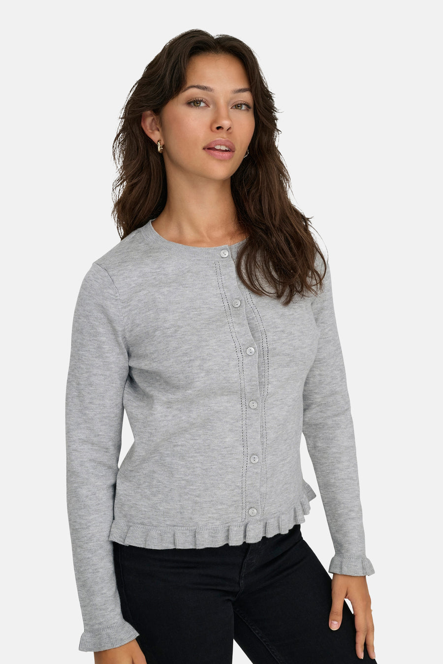 Cardigan gris de ONLY, avec une rangée de boutons et ourlet à volants, porté avec un pantalon noir.
