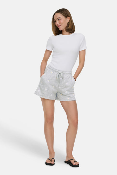 Short gris ONLY® avec un motif marguerite, porté avec un t-shirt blanc et des tongs noires.