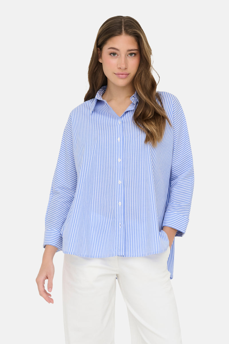 Chemise à manches longues bleu rayé de ONLY®, portée avec un pantalon blanc.