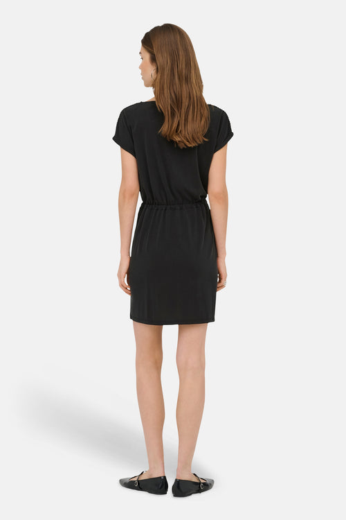 Robe noire de ONLY®, vue de dos, à manches courtes, avec taille coulissée, portée avec des chaussures plates noires.