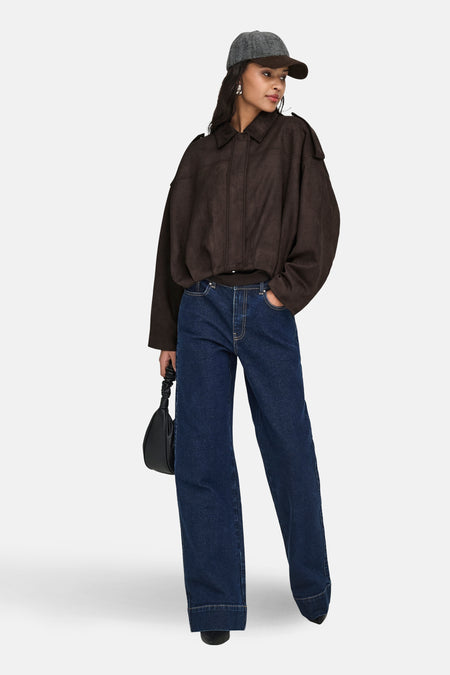 Veste courte marron de JDY, avec un col classique, portée avec un jean ample et un sac à main noir.
