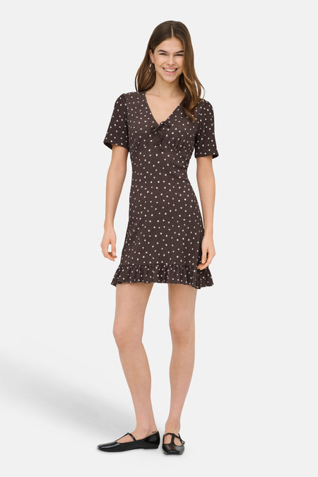 Robe courte brune de ONLY® à pois blancs, manches courtes, encolure en V à nœud et ourlet volanté.
