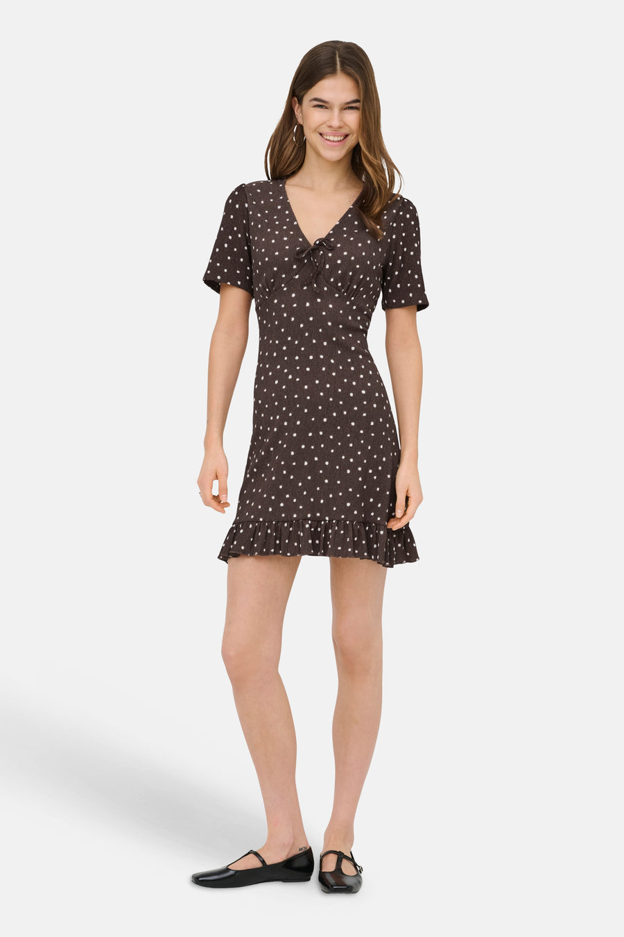 Robe courte brune de ONLY® à pois blancs, manches courtes, encolure en V à nœud et ourlet volanté.