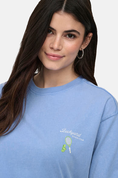 T-shirt bleu de ONLY® à manches longues, avec l'inscription "Backyard tennis tour" et une raquette de tennis verte brodée sur la poitrine.