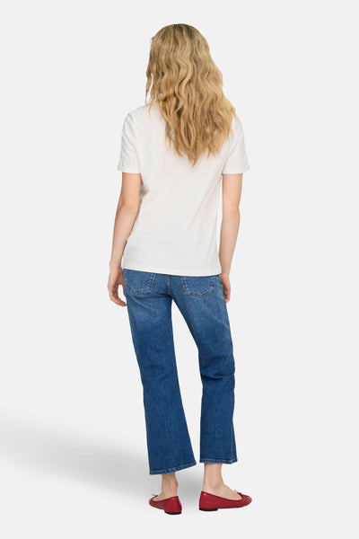 Wit T-shirt met korte mouwen van ONLY, gedragen met een blauwe jeans en rode ballerina's.