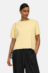 Pull jaune à col rond de JDY, porté avec un pantalon noir fluide et un sac à chaîne.