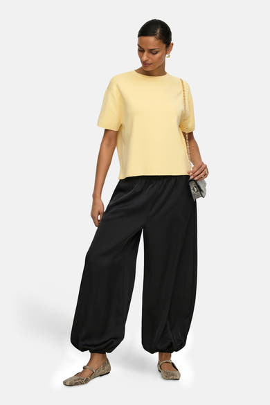 Pull jaune col rond de JDY, porté avec un pantalon noir ample et des ballerines à motif peau de serpent.