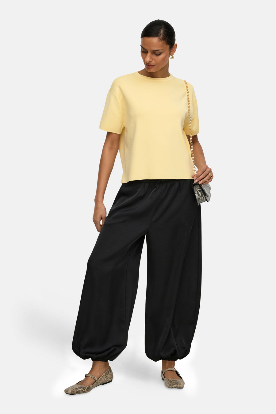 Pull jaune col rond de JDY, porté avec un pantalon noir ample et des ballerines à motif peau de serpent.