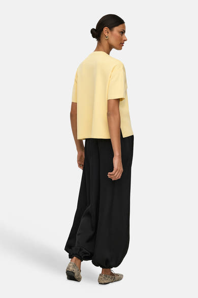 Pull jaune, de JDY, porté avec un pantalon noir ample et des chaussures à imprimé serpent.