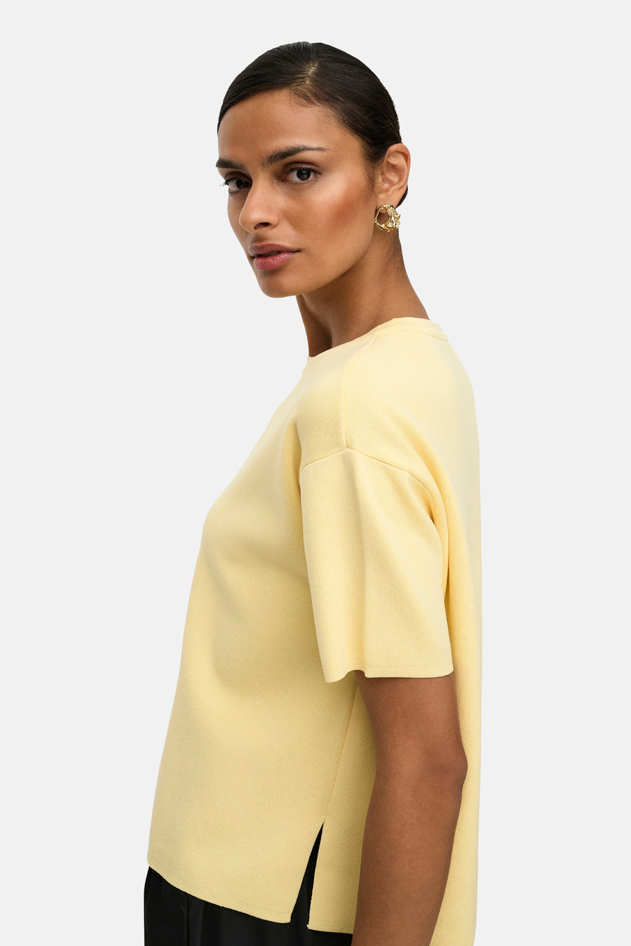 Pull jaune à col rond de JDY, porté avec des boucles d'oreilles dorées.